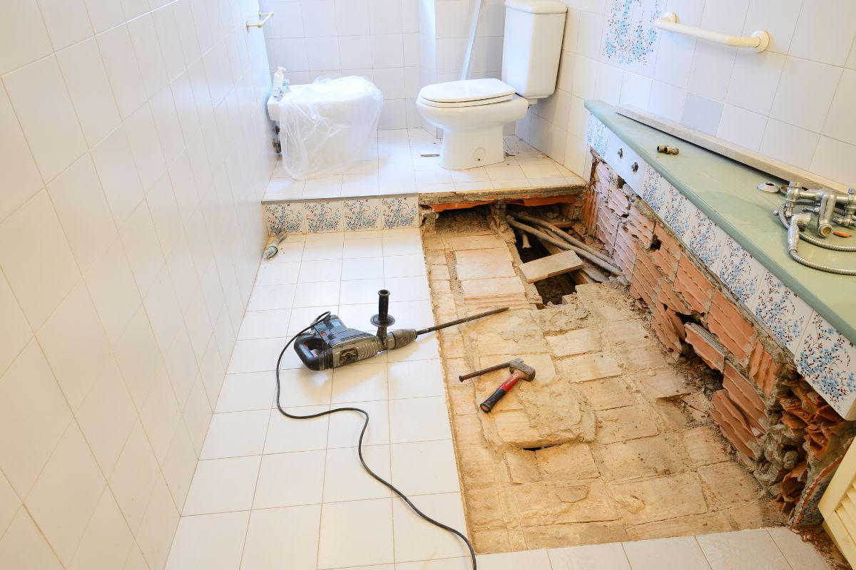 a typical bathroom demolition scene with tiles being removed from the floor