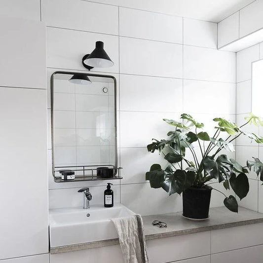 Modern bathroom with white tiles, a mirror, sink, and potted plant. Tiles are dolce white matt ceramic tiles